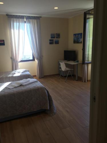a bedroom with a bed and a desk and window at Residence La Canonica in Costa Valle Imagna