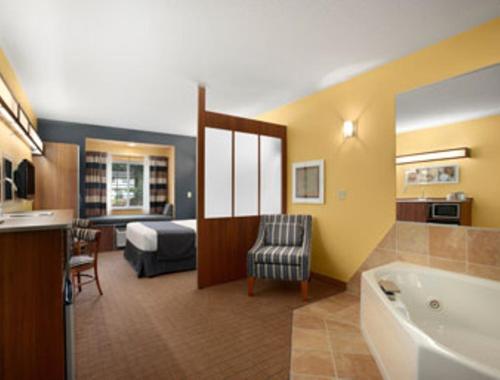 a hotel room with a bed and a bathroom at Microtel Inn & Suites Chili/Rochester in Chili Center