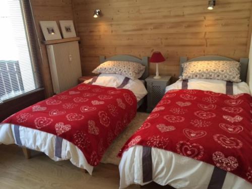 - 2 lits dans une chambre avec des couvertures rouges et blanches dans l'établissement Luxury Apartment, 350m to ski lift, south facing, close to town centre, à Morzine