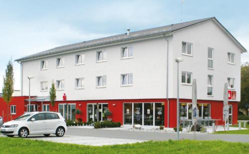 ein weißes Auto, das vor einem Gebäude parkt in der Unterkunft Gästehaus Adler in Biberach an der Riß