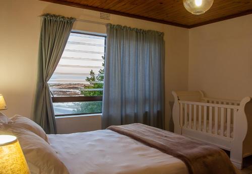 a bedroom with a crib and a large window at Rots en See in Gansbaai