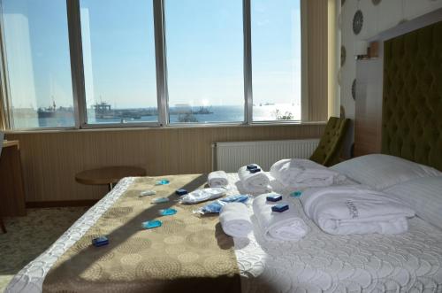 a hotel room with towels on a bed with windows at Lounge Hotel in Tuzla