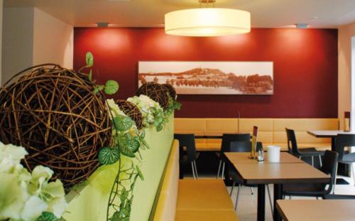 ein Restaurant mit Tischen und Stühlen und eine Wand mit Pflanzen in der Unterkunft Gästehaus Adler in Biberach an der Riß
