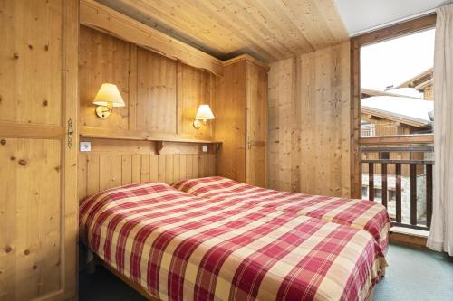 ein Schlafzimmer mit einem Bett in einem Zimmer mit Holzwänden in der Unterkunft Résidence Les Balcons de La Rosière in La Rosière