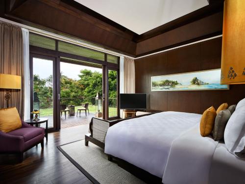 a bedroom with a large white bed and a balcony at The Anvaya Beach Resort Bali in Kuta