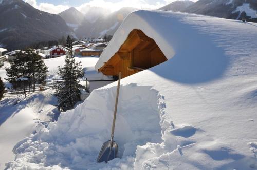 ein schneebedecktes Haus mit einer Schaufel im Schnee in der Unterkunft Landhaus Lisa in Schladming