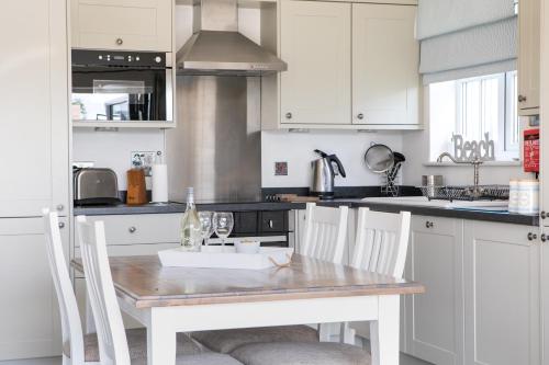 a kitchen with a wooden table and white cabinets at The Bay Filey in Filey