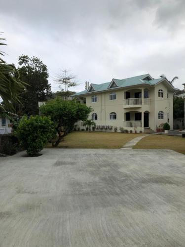 a large white house with a large driveway at Flower Garden Self-Catering Apartments in Beau Vallon