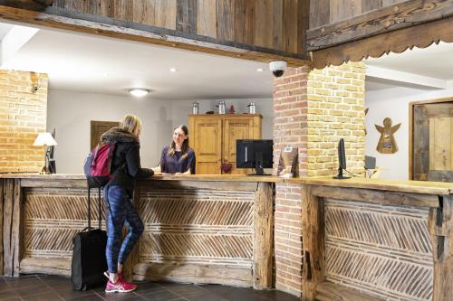 dos mujeres de pie en un bar en un edificio en Résidence Les Balcons de Val Cenis Village, en Lanslevillard