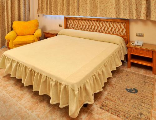 a bedroom with a large bed and a yellow chair at KAKTUS Hotel Kaktus Albir in Albir