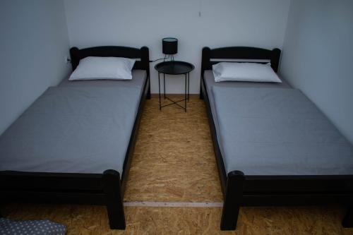 two twin beds in a room with a stool at OPG Dokić in Kopačevo