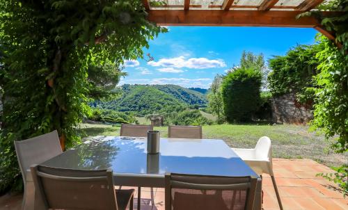 a table and chairs on a patio with a view at La Ferme du Cayla in Linac