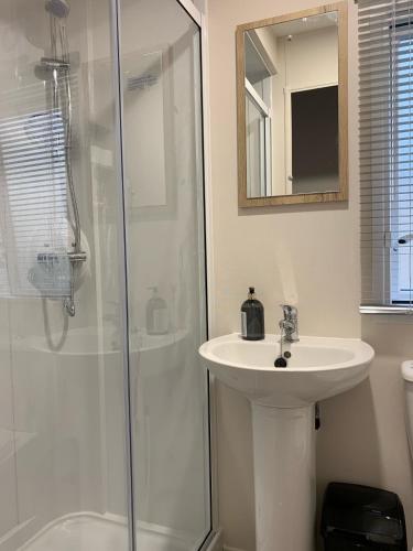 a white bathroom with a sink and a shower at Brambles 66 -Static Holiday Caravan, Porthcawl in Newton