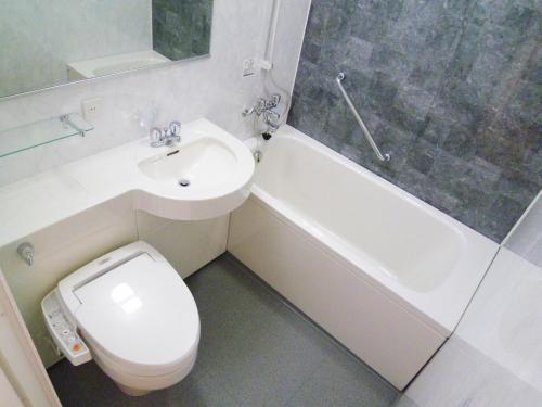 a white toilet sitting next to a bath tub in a bathroom at Hearton Hotel Kita Umeda in Osaka