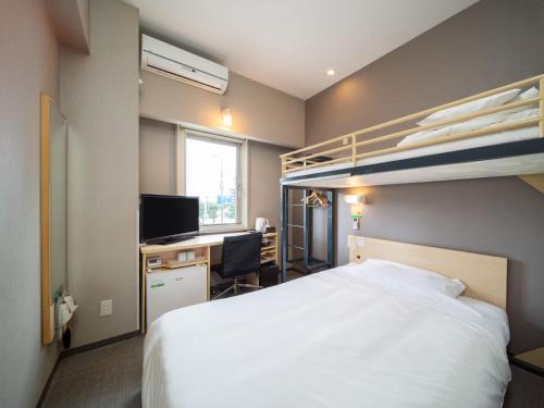 a bedroom with a bed and a desk and bunk beds at Super Hotel Fuji Inter in Fuji