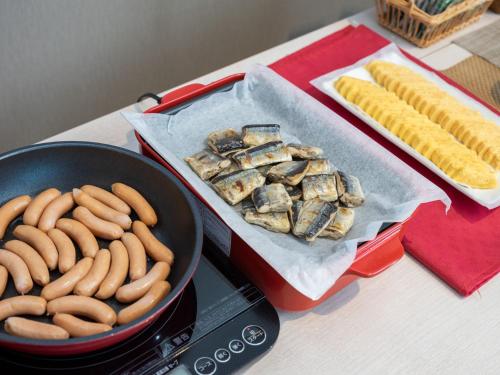 a table with a pan of hot dogs and a pan of food at Super Hotel Fuji Inter in Fuji