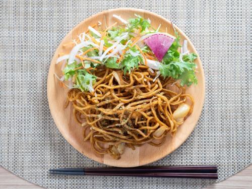 a plate of noodles and vegetables on a table with chopsticks at Super Hotel Fuji Inter in Fuji