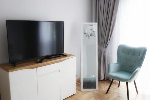 a television sitting on a white cabinet with a blue chair at AMN APARTMENTS in Warsaw