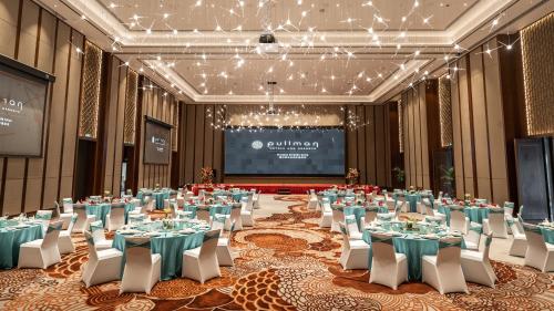 a banquet hall with tables and chairs and a projection screen at Pullman Huizhou Kaisa in Huizhou