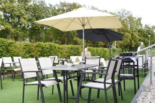 a table and chairs with an umbrella on the grass at Hôtel des Mosaiques in Orbe