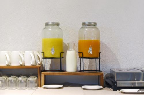 two glass jars filled with orange juice on a shelf at Hôtel des Mosaiques in Orbe