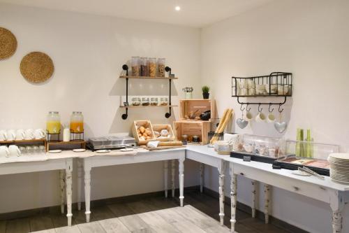 a kitchen with two white tables in a room at Hôtel des Mosaiques in Orbe