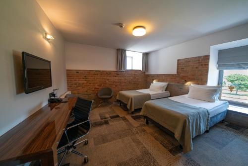a hotel room with two beds and a television at Q Hotel Grand Cru Gdańsk in Gdańsk