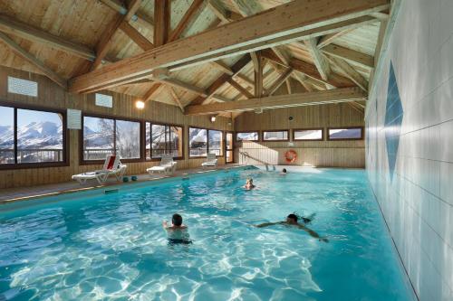 un groupe de personnes nageant dans une piscine dans l'établissement Résidence Néméa Les Chalets Des Cîmes, à La Toussuire