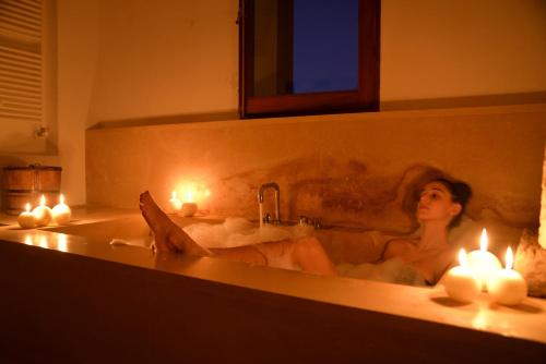 a woman sitting in a bath tub with lit candles at Masseria Autigne in Otranto
