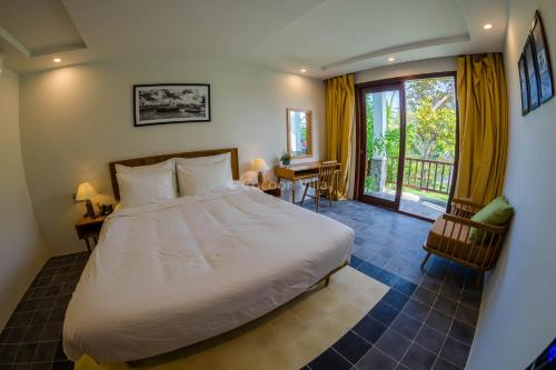 a bedroom with a large bed and a balcony at Cocoon Villa in Hoi An