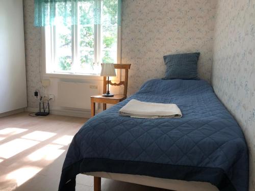 1 dormitorio con 1 cama con edredón azul y ventana en Sättraby villa, en Norrtälje