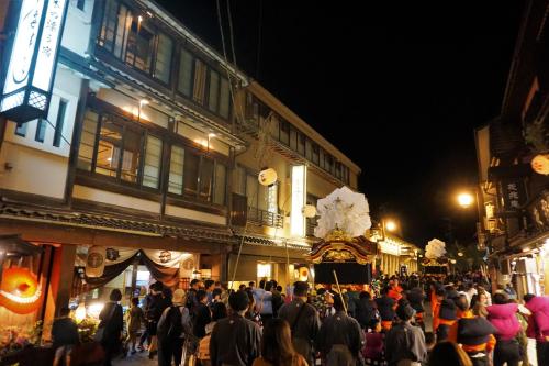a crowd of people walking down a street at night at Morizuya in Toyooka