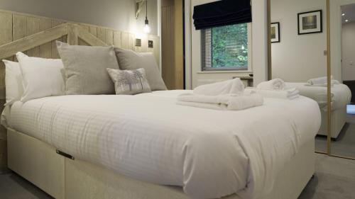 a large white bed with white sheets and pillows at Hill Of Oaks in Windermere