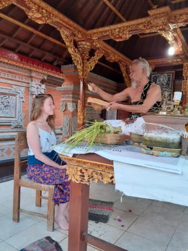 Zwei Frauen sitzen mit Gemüse an einem Tisch. in der Unterkunft Griya Bun Sari in Sukawati