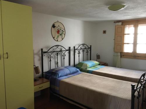 a bedroom with two beds and a clock on the wall at Giuditta in Putzu Idu