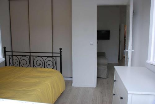 une chambre avec un lit avec une couverture jaune dans l'établissement quartier Pavillonnaire, à Rosny-sous-Bois