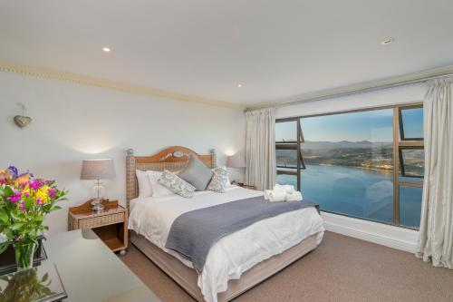 a bedroom with a bed and a large window at Villa Castollini in Brenton-on-Sea