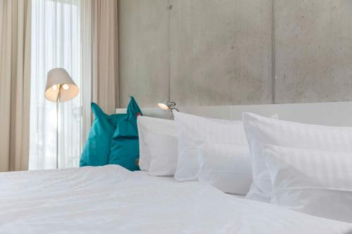 ein weißes Bett mit weißen Kissen und einem blauen Kissen in der Unterkunft Factory Hotel in Münster