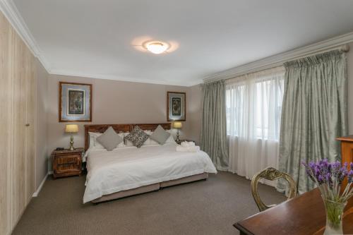 a bedroom with a large white bed and a table at Villa Castollini in Brenton-on-Sea