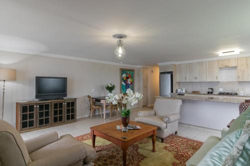 a living room with couches and a table and a kitchen at Villa Castollini in Brenton-on-Sea
