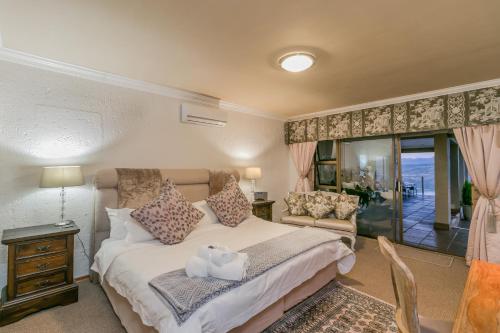 a bedroom with a bed and a couch and a window at Villa Castollini in Brenton-on-Sea