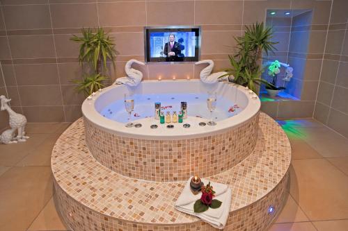 a jacuzzi tub in a room with a tv at Windermere Boutique Hotel Spa Suites & Hot Tubs in Windermere