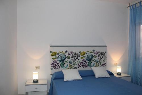 a bedroom with a blue bed with a floral headboard at Cala Gavetta 5 in La Maddalena