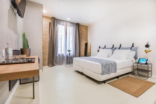 a white bedroom with a bed and a desk at Casa Lirio in Barcelona