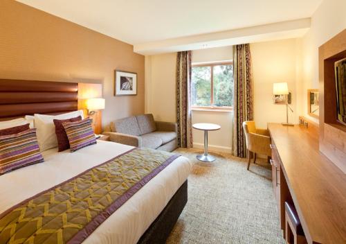 タムワースにあるドレイトン マナー ホテルのベッドとリビングルームが備わるホテルルームです。