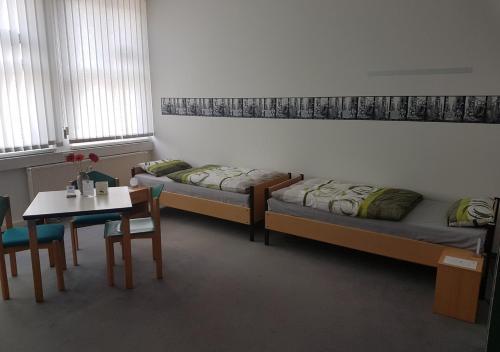 a room with two beds and a table and a table and chairs at Hostel jo-si in Kamenz