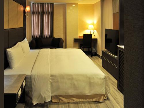 a hotel room with a large bed and a desk at Maple Hotel Second Branch in Tainan