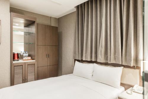 a bedroom with a bed with white pillows at Maple Hotel Second Branch in Tainan