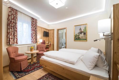 a hotel room with a bed and a chair at Hotel-Restaurant Kirchenwirt in Weissenkirchen in der Wachau