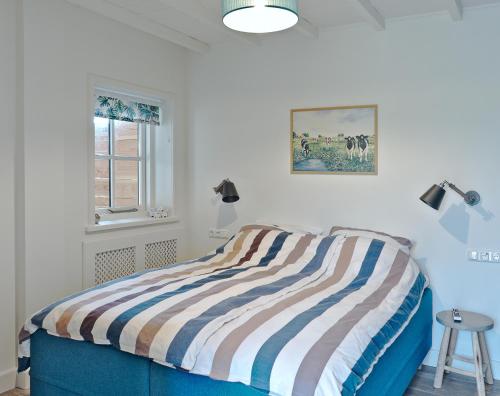 een slaapkamer met een bed met een gestreepte deken bij B&B d'n Uilenhof Haren in Haren